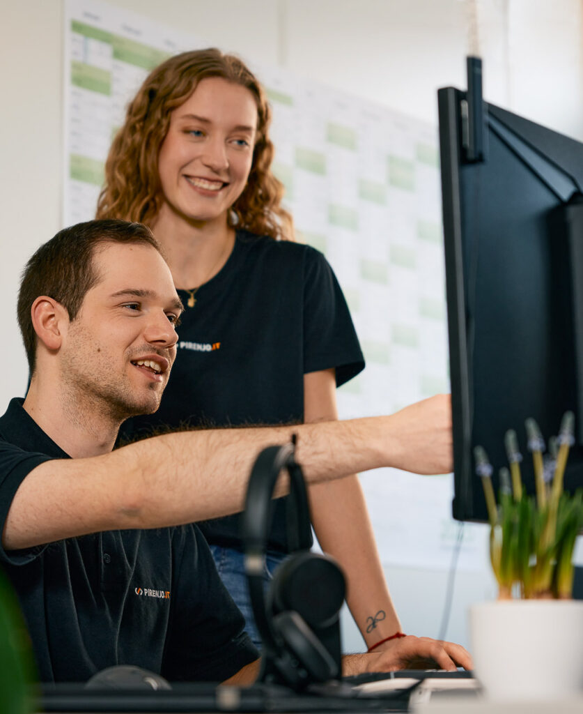 Mitarbeiter zeigt Kollegin etwas am Bildschirm.