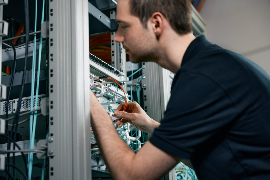 Mitarbeiter überprüft Netzwerkkabel im Serverraum.